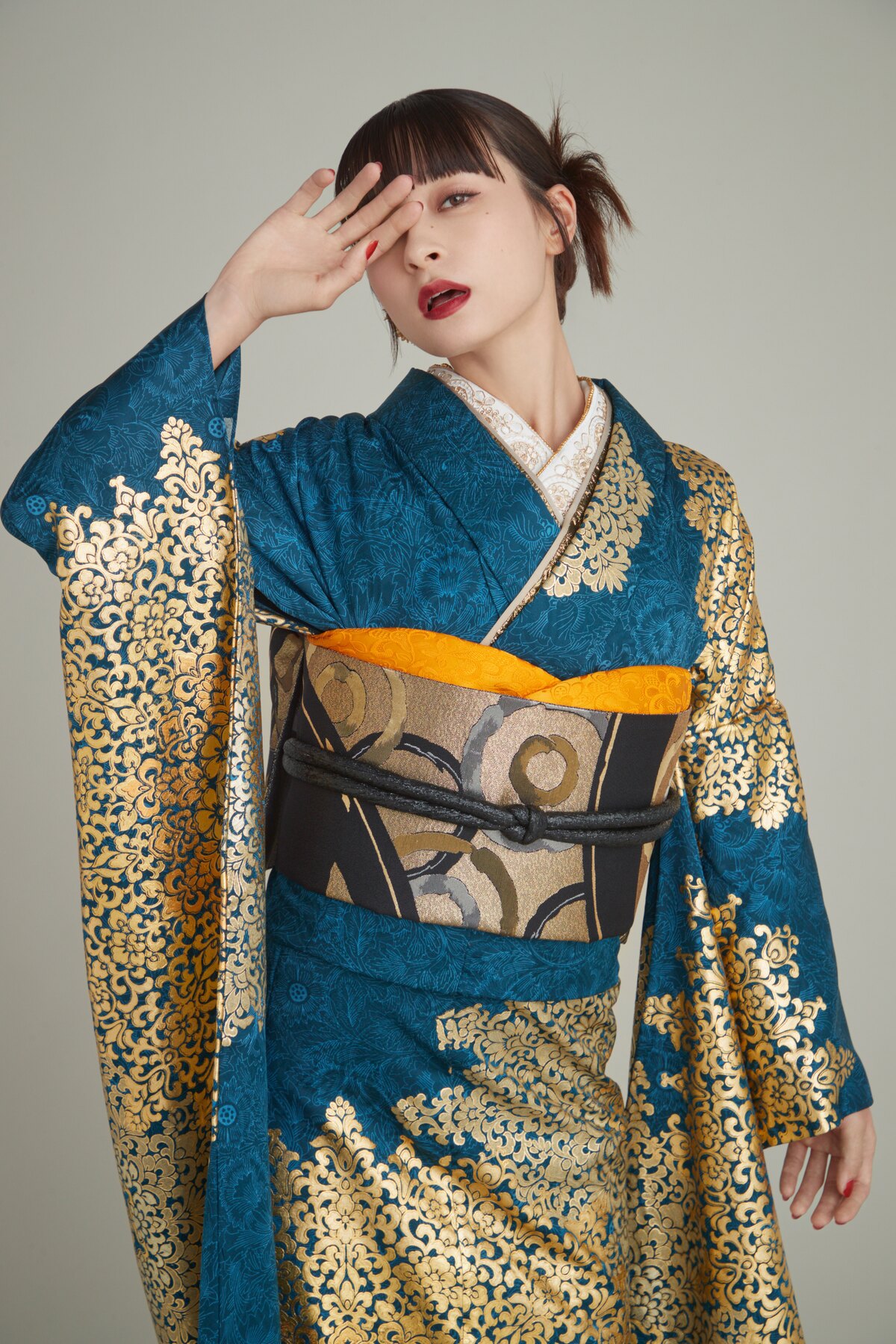 青緑と金の振袖をファッショナブルに着こなす女性