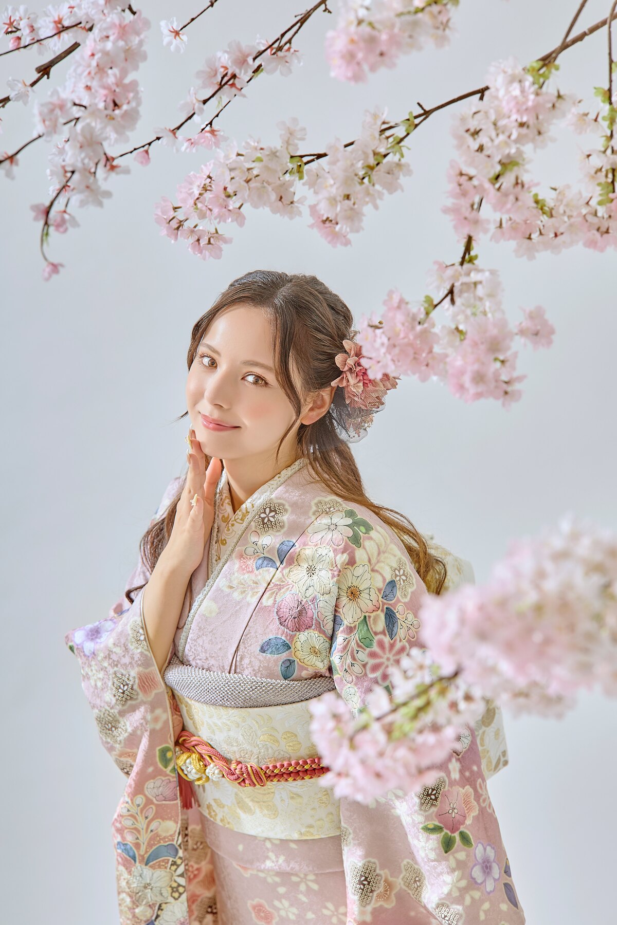 淡い花柄の振袖を桜の下でやわらかく着こなす女性